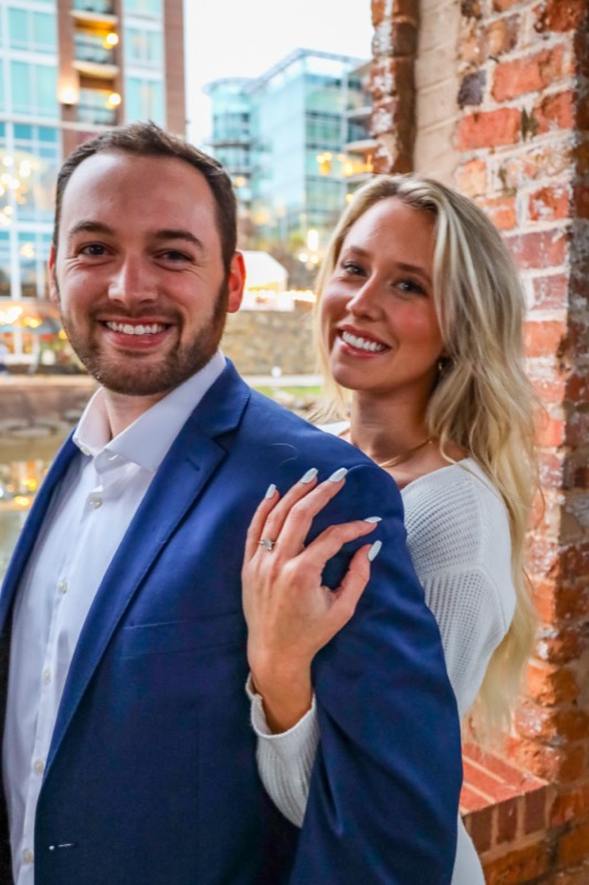 Newly engaged, smiling at the camera with the ring showing
